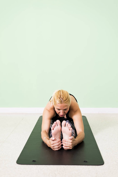 Frau praktiziert Yoga sitzend in paschimottanasana (sitzend forwa - Foto, Bild