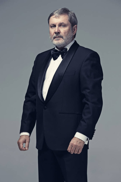 Middle aged male adult wearing a suit isolated on gray - Фото, изображение