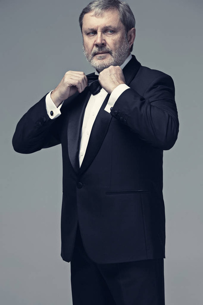 Middle aged male adult wearing a suit isolated on gray - Foto, afbeelding