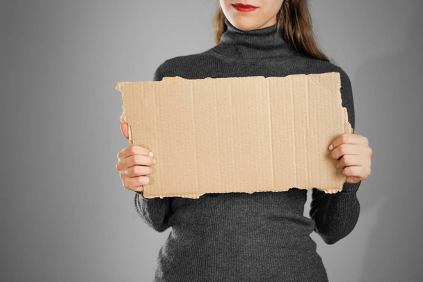 A young girl in a grey jacket holding a piece of cardboard. Prep - Foto, Imagen