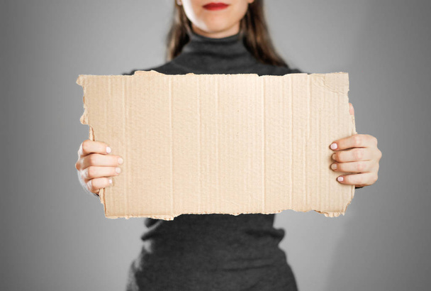 A young girl in a grey jacket holding a piece of cardboard. Prep - Foto, Imagem