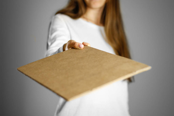 Молодая девушка в белом пиджаке держит кусок картона. Пре
 - Фото, изображение