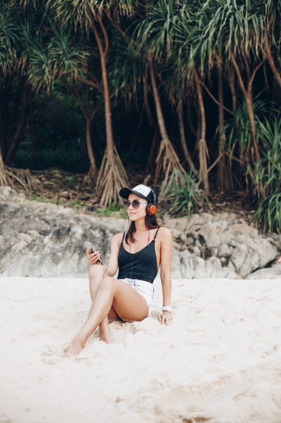 young woman listening music with headphones at tropical beach - Valokuva, kuva
