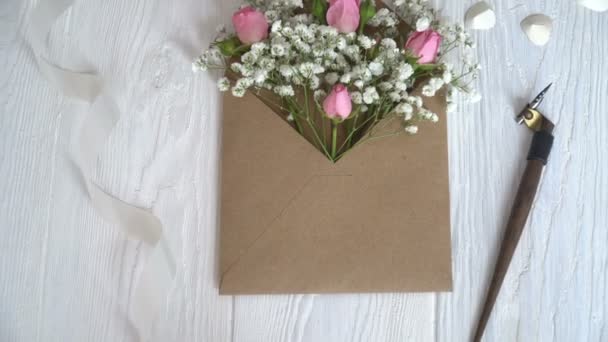 Kraft koperty z kwiatami na drewniane białe tło z długopisu kaligraficzne - Materiał filmowy, wideo
