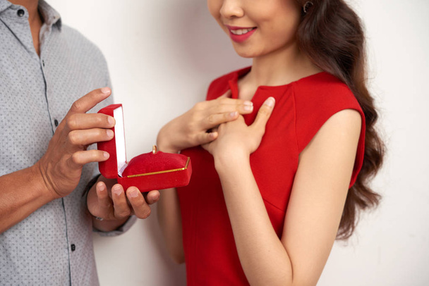 hombre sosteniendo caja roja con anillo en las manos mientras hace propuesta de matrimonio a su novia
 - Foto, Imagen