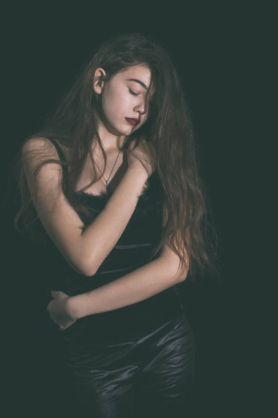 Fiatal lány pózol a fekete háttér, hosszú hajjal - Fotó, kép
