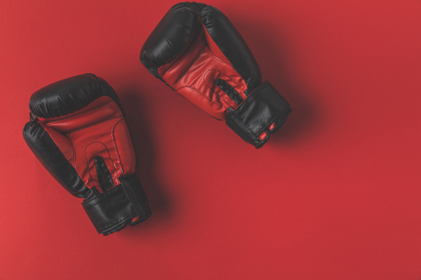 top view of boxing gloves lying on red tabletop - Fotó, kép