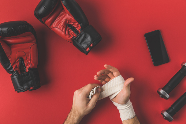обрізаний знімок боксера, що покриває руки в еластичній пов'язці на червоній поверхні
 - Фото, зображення