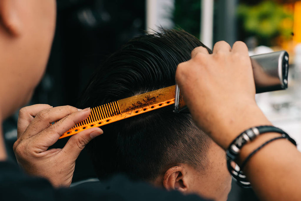 Imagem close-up de cabeleireiro usando pente especial para aparar cada pedaço de cabelo que é muito longo
 - Foto, Imagem