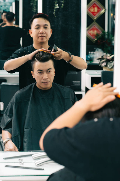 Young Vietnamese man visiting hairdresser to get new haircut - Photo, Image