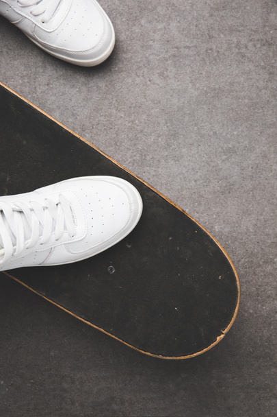 top view of white shoes on skateboard on gray concrete surface - Φωτογραφία, εικόνα