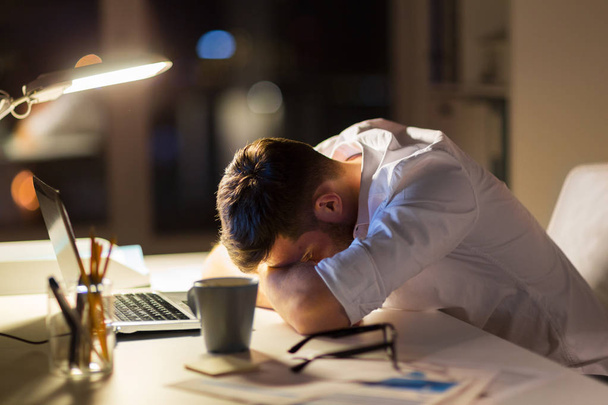 tired businessman lying on table at night office - Foto, Bild