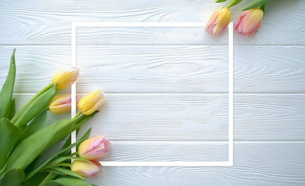 schöne Tulpenblumen auf weißem Holzhintergrund mit Rahmen, Urlaubspostkarte für Frauentag oder Muttertag oder Verkaufskonzept. Floraler Frühling Hintergrund mit Kopierraum. flache Lage. - Foto, Bild