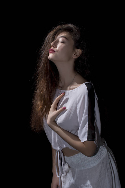 Young girl with long hair posing on black background - Foto, Imagen