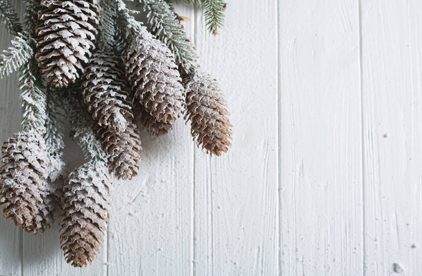 Christmas background with fir branches and cones. White wooden boards. Snow-covered winter background - Photo, Image