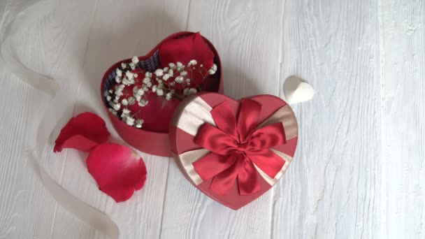 Δώρο κουτί με μορφή καρδιά και κόκκινης κορδέλλας σε ξύλινο λευκό φόντο. Το Top view - Πλάνα, βίντεο