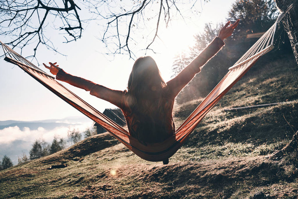back view of woman relaxing in hammock and enjoying autumn in mountains - Photo, Image