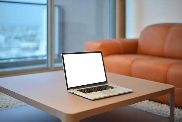 Laptop op tafel in moderne woonkamer met leeg scherm - Foto, afbeelding
