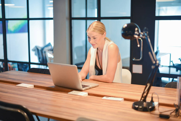 Ευτυχισμένος επιχειρηματικό χρησιμοποιώντας ένα φορητό υπολογιστή σε ένα γραφείο ξανθιά κοπέλα - Φωτογραφία, εικόνα