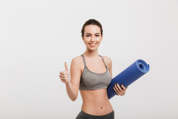 young woman with yoga mat showing thumb up isolated on white - Foto, immagini