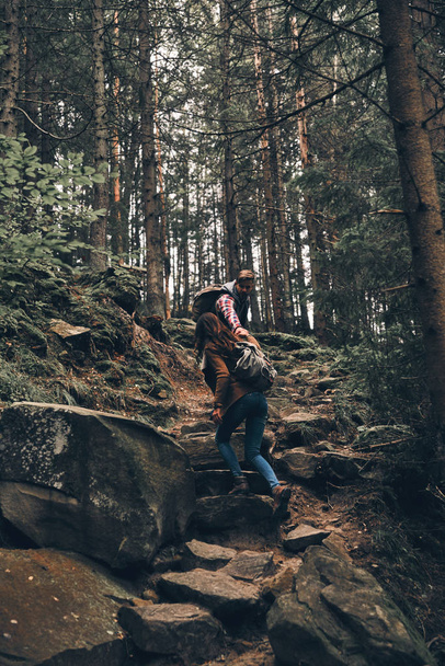 handsome man holding hands and moving up his girlfriend while hiking in mountains on rock stairs - Foto, immagini