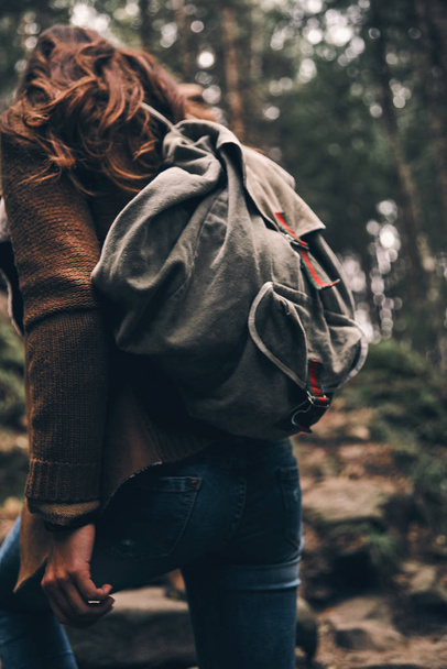 Rear view of woman with backpack moving up while hiking in wood - Фото, зображення