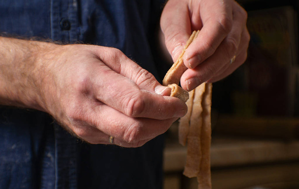 Чоловік розкриває тісто для макаронних виробів збоку
 - Фото, зображення