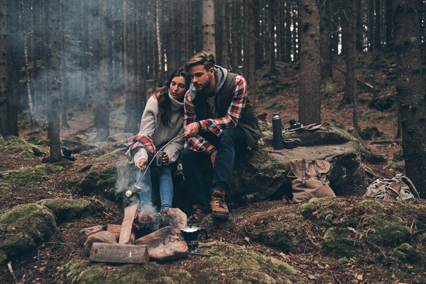 tourists couple near bonfire in mountains wood - Photo, Image