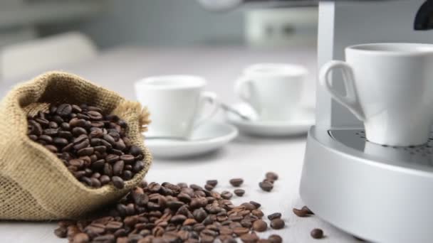 koffiezetapparaat ingebruikzijn vult twee witte kop met koffiebonen op tafel. Clip met cirkelvormige beweging schieten. - Video