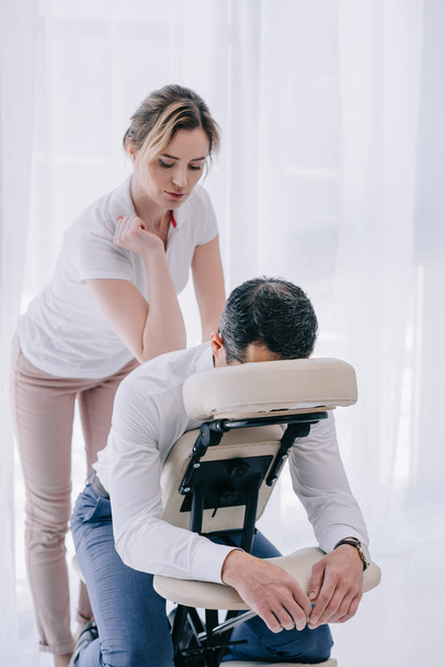 massaggiatrice professionista che fa massaggio alla schiena seduto per uomo d'affari
 - Foto, immagini
