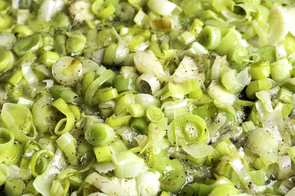 Свіжий зелений цибуля-порей, що сидить в іржавій сковороді на плиті
 - Фото, зображення