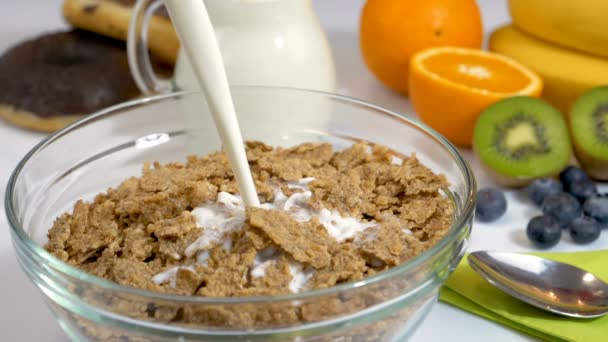 Gieten melk op graan vlokken voor gezond en biologisch ontbijt. Slow-motion shot. - Video