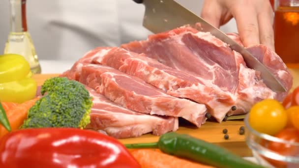 Vrouw handen snijden van vers rauw vlees voor het koken met groenten in de keuken. Slow-motion shot. - Video