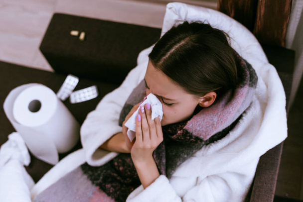 a sick woman with a warm scarf to blow her nose - Zdjęcie, obraz