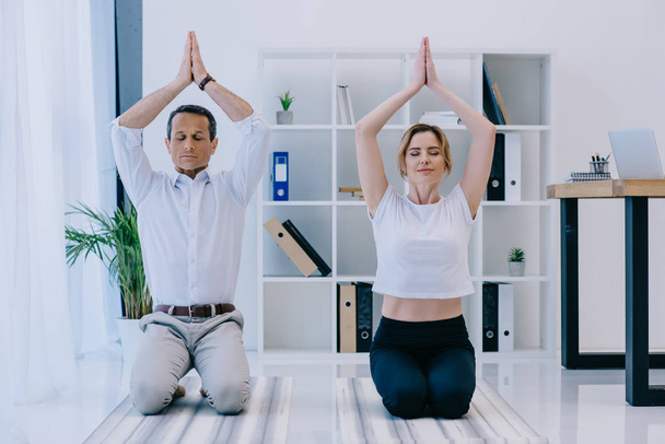 mature businessman with his trainer meditating on yoga mats at office - Fotoğraf, Görsel