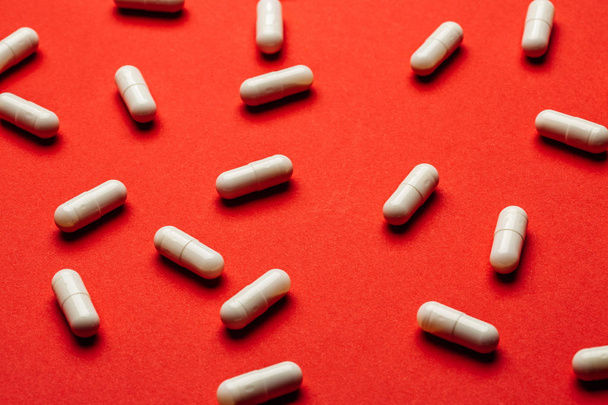 Many white pills on red background. Medicine and pharmacy concept. - Photo, Image