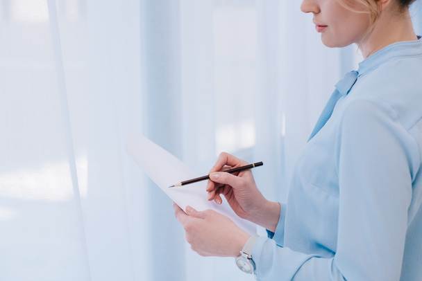 cropped shot of businesswoman with pencil reading document - Фото, зображення