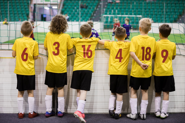 Indoor soccer team. Futsal indoor soccer match for kids. Children supporting teammates. Sports arena in the background. Indoor football school tournament for kids - Photo, Image