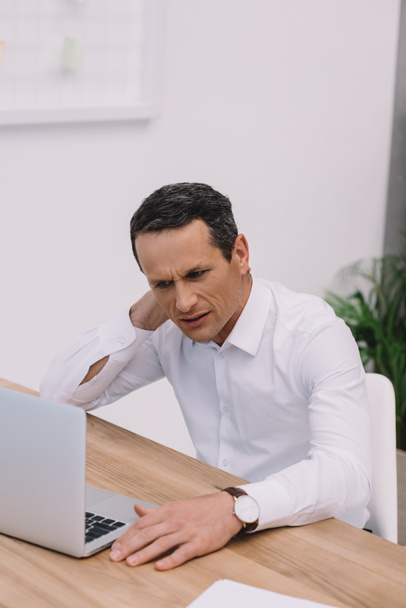 homme d'affaires mature avec douleur au cou travaillant avec un ordinateur portable au bureau
 - Photo, image