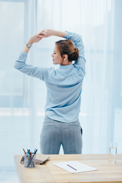 visão traseira de empresária atraente fazendo ginástica matinal no escritório
 - Foto, Imagem