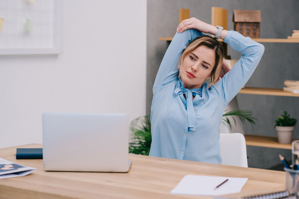 деловая женщина растягивает плечи на рабочем месте в офисе
 - Фото, изображение