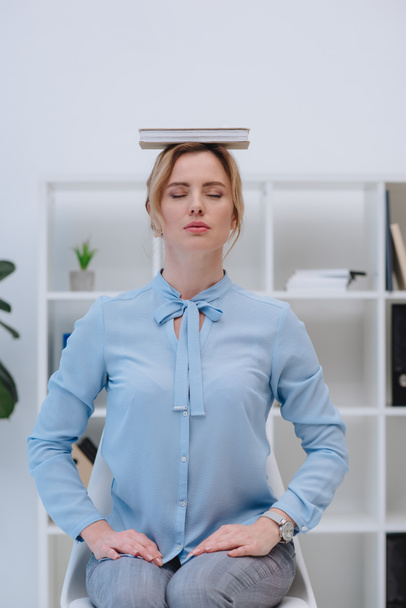 hermosa mujer de negocios meditando con libro en la cabeza en la oficina
 - Foto, Imagen