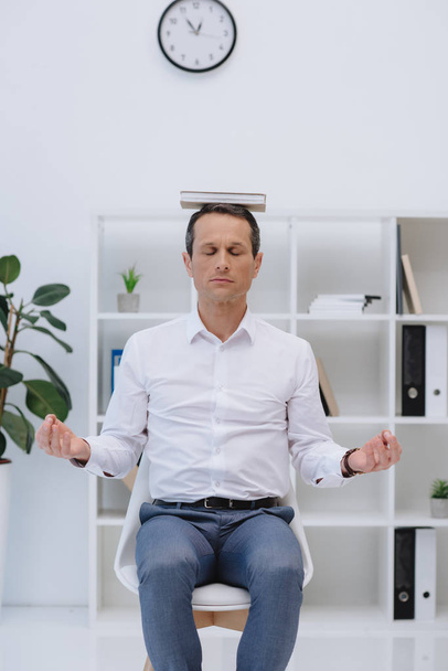pro dospělé podnikatel meditovat s knihou na hlavě v kanceláři - Fotografie, Obrázek