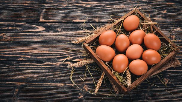 Chicken raw eggs in a wooden basket. On a wooden background. Top view. Copy space. - Foto, Imagen