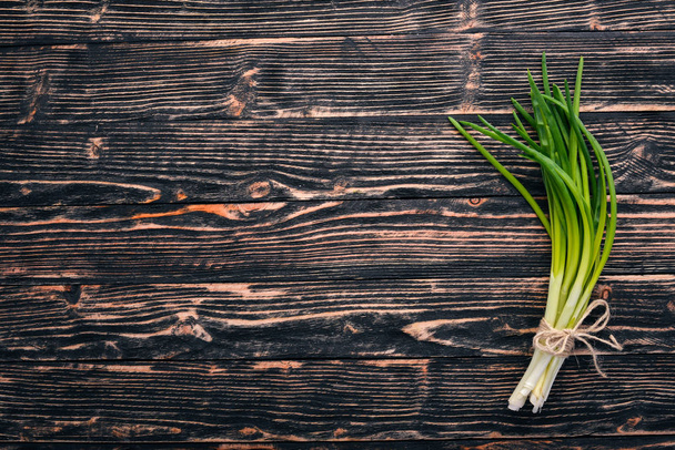 Fresh green onion on a wooden background. Top view. Free space for your text. - Foto, imagen