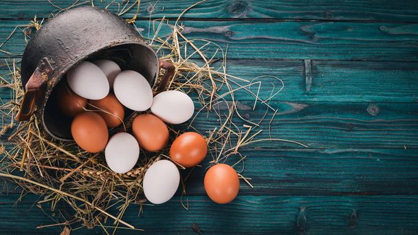 Chicken eggs in a metal saucepan. On a wooden background. Top view. Copy space. - Foto, Bild