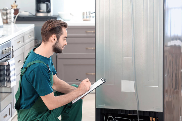 Male technician during repair of refrigerator indoors - Photo, Image