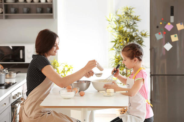 Mother and daughter preparing dough indoors - Foto, afbeelding