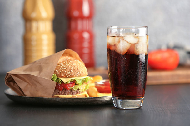 Glass of cold cola with tasty burger on table - Valokuva, kuva