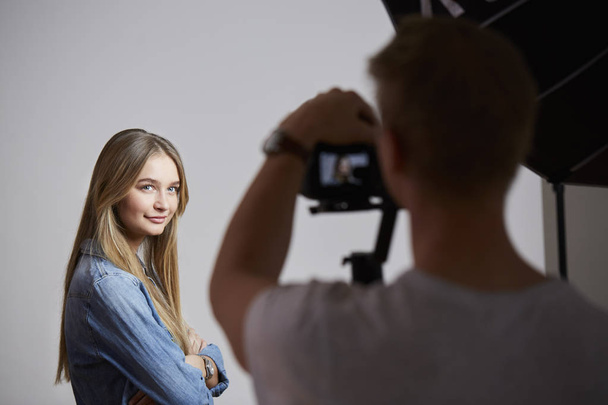 Young woman posing in studio for photographer - Zdjęcie, obraz